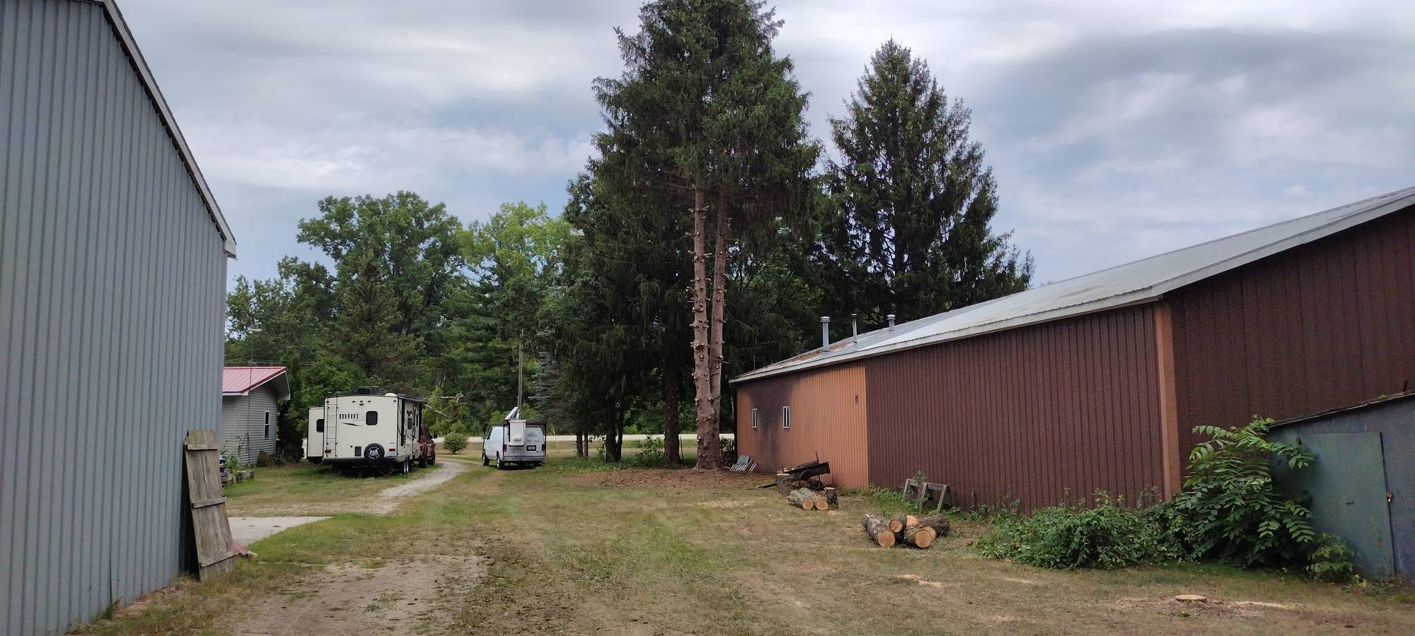 Same property after tree removal between a gray building and red barn